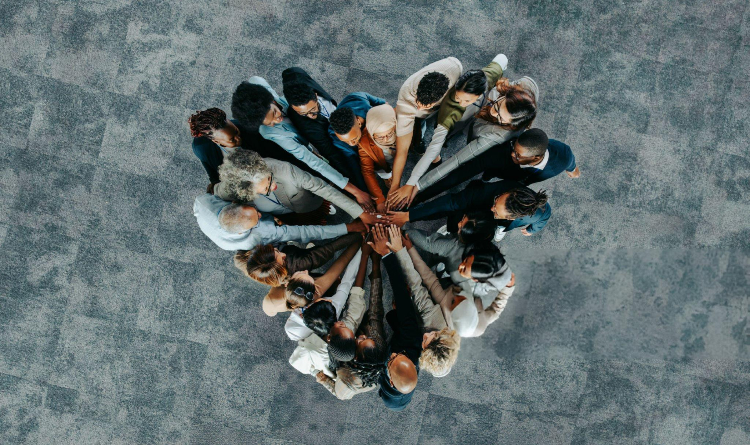 Groupe de personnes diverses formant un cercle et joignant leurs mains au centre